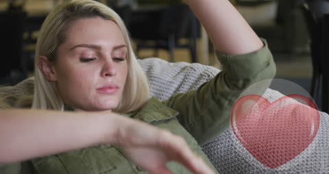 Young Woman Relaxing on Sofa with Heart Graphic Overlay