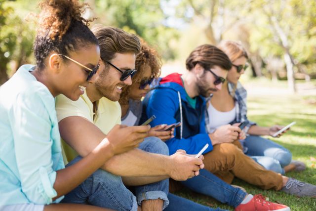 Group of friends using mobile phone in park