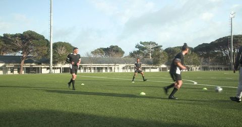 Competitive soccer players practicing with cones on green field