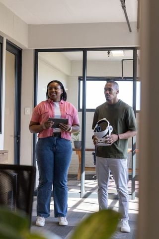 African american coworkers demonstrating vr headset and tablet in modern glass office