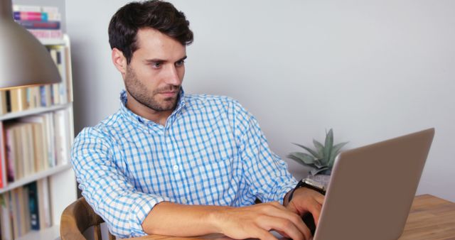 Concentrated man using laptop at home