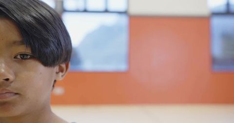 Gazing asian boy with neutral expression and orange background