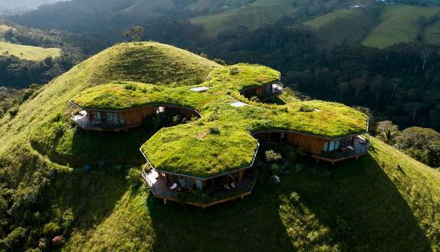 Green-roof eco lodges nestling on hilltop ridge with terraced wooden decks and views