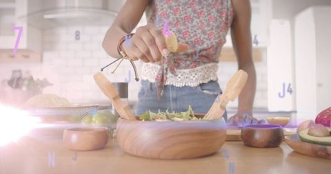 Woman Prepares Fresh Salad in Modern Kitchen with Citrus Touch