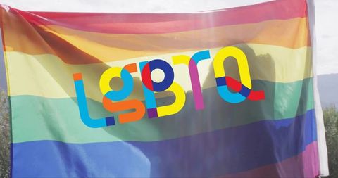 Waving rainbow pride flag featuring colorful lgbtq lettering and sun flare