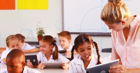 Teacher assisting student with tablet in modern digital classroom