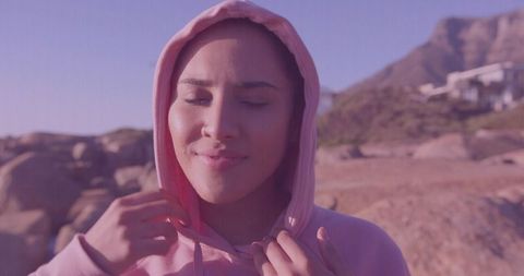 Woman wearing pink hoodie standing on rocky desert enjoying peaceful sunrise moment
