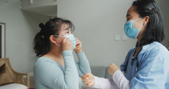 Asian female nurse and patient wearing face masks talking and looking to camera in hospital. medicine, health and healthcare services during coronavirus covid 19 pandemic.