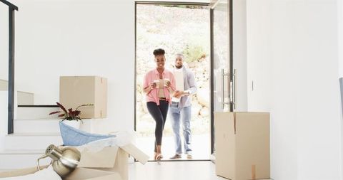 Happy Couple Entering New Home with Boxes and Coffee During Move