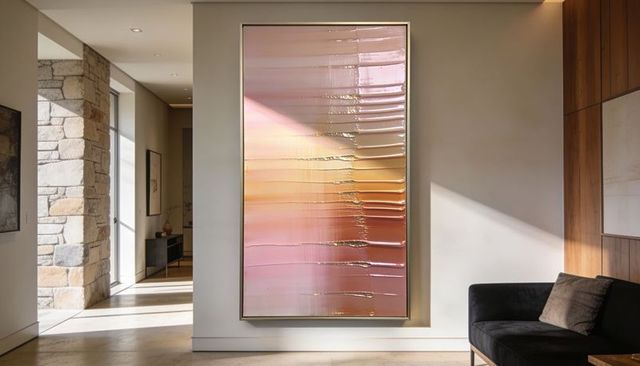 Glossy gold and rose abstract canvas reflecting sunlight in modern foyer with sofa