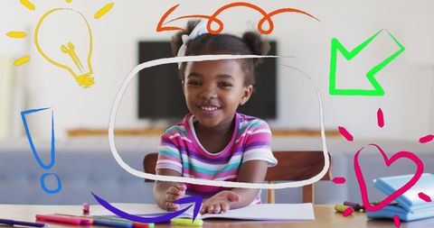 Joyful girl drawing at desk with colorful markers