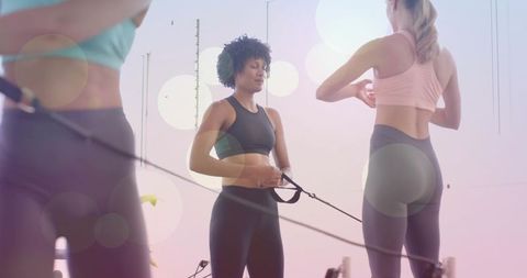 Women holding reformer straps and practicing pilates reformer training in pastel studio