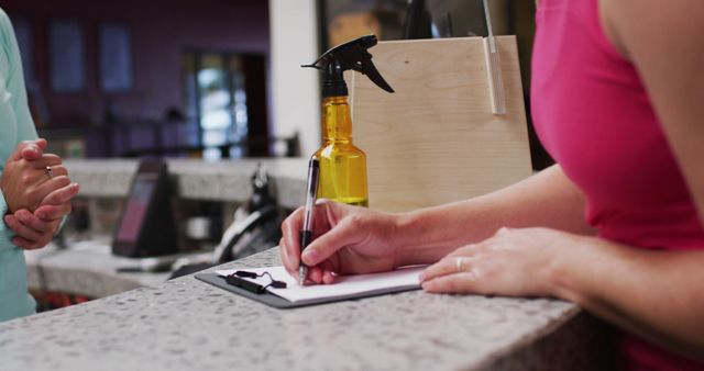 Woman is signing in at fitness center reception. Can be used for advertising gyms, fitness center services, customer service, or membership registration processes.