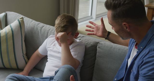 Caucasian father talking with his sad son and sitting in living room - Download Free Stock Photos Pikwizard.com