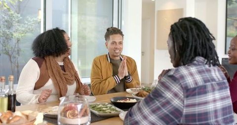 Diverse Friends Sharing Warm Meal Around Modern Dining Table During Casual Home Gathering