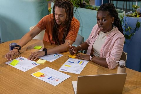 Multiracial coworkers collaborating on charts and sticky notes in modern office workspace