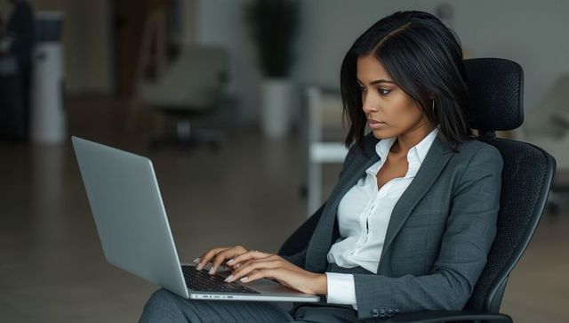 Focused Professional Woman Typing on Laptop in Modern Office Environment