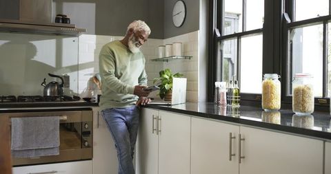 Mature man using smartphone in contemporary kitchen setting