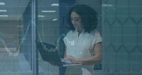 Businesswoman analyzing financial market data on laptop with transparent charts overlay