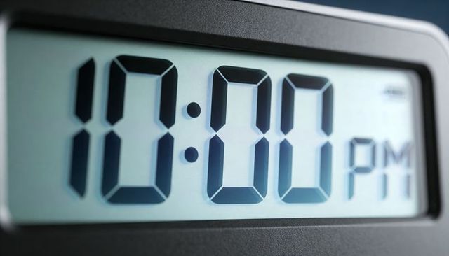 Closeup digital alarm clock displaying 10:00 pm seven-segment minimalist modern bedside