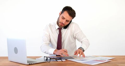 Young Businessman Multitasking at Work with Documents and Laptop