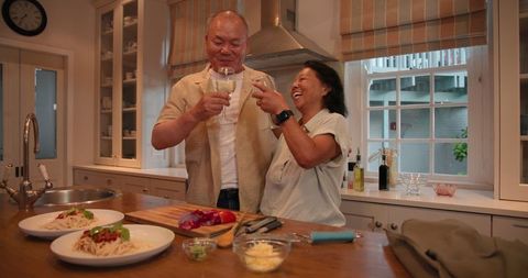 Senior asian couple enjoying cooking and wine at home