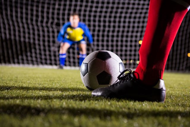 Image depicts a soccer player preparing to take a penalty kick with the goalkeeper in the background. Ideal for use in sports-related articles, advertisements for soccer gear, or motivational content about teamwork and competition.