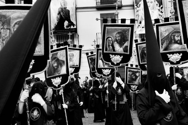 Timeless capture of a Catholic Holy Week procession featuring hooded participants carrying religious icons. Perfect for illustrating religious traditions, articles on Catholicism, historical reenactments, or promoting cultural tourism.