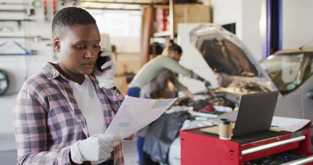 Female Auto Mechanic Discussing Repair Strategies on Phone in Garage - Download Free Stock Images Pikwizard.com