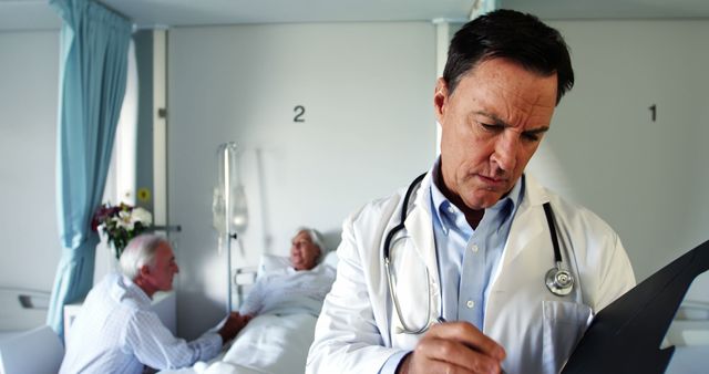 Doctor reviewing medical records in hospital room while elderly patient and visitor interact in background. Suitable for themes on healthcare, medical care, patient visits, medical education, elderly care, doctor-patient interaction.