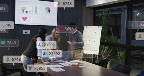 Team analyzing sales dashboard and social notifications at conference table for strategic planning