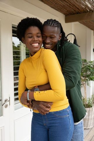 Joyful Couple Embracing on Sunlit Porch in Relaxed Home Atmosphere