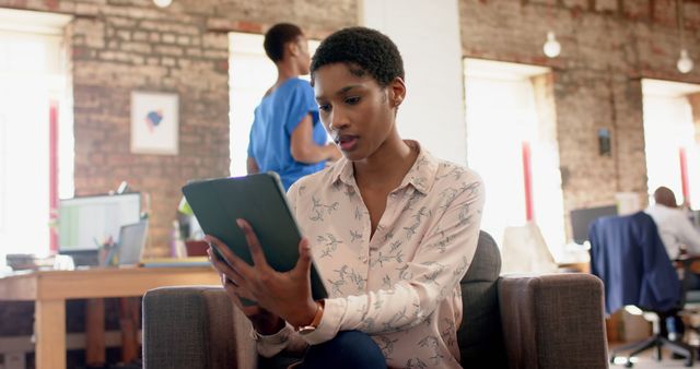 A focused professional uses a tablet in a modern office space. This image is ideal for concepts related to business, technology, modern workplaces, productivity, and professional life. It can be used in corporate presentations, promotional materials for tech companies, or articles about digital transformation and work environments.