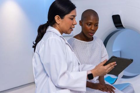 Female doctor reviewing mri scan with female patient on tablet in radiology consultation
