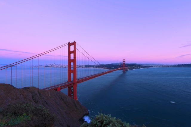 Golden Gate Bridge is spanning calm waters during vivid sunset. Ideal for showcasing exquisite travel destinations, iconic architectural marvels, postcard designs, San Francisco tourism campaigns, blog posts about West Coast adventures, and scenic landscape artworks.