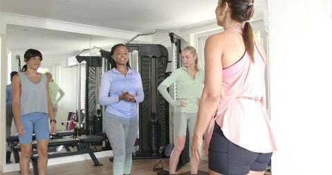 Group of diverse women engaging in fitness class with trainer