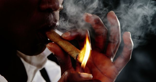 Person lighting cigar with flame in hand amidst smoke - Download Free Stock Images Pikwizard.com