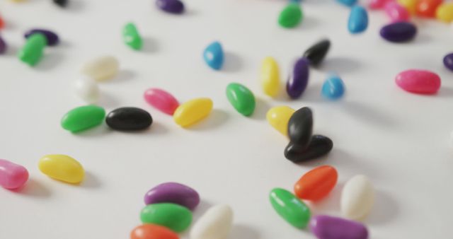 Vibrant colorful jelly beans scattered on white background. Ideal for illustrating fun, playful themes, candy shop promotions, or children’s party invitations. Can be used in food blogs, advertisements, or packaging designs for confectionery products.