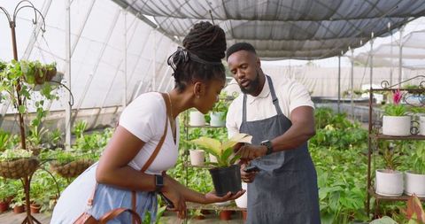 Gardener Explaining Plant Care in Greenhouse Nursery