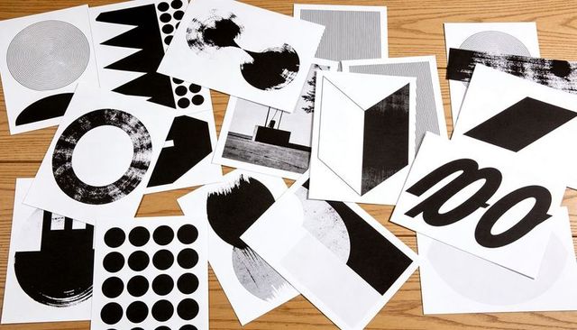 Black and white abstract graphic prints scattered on wood table modern pattern flatlay