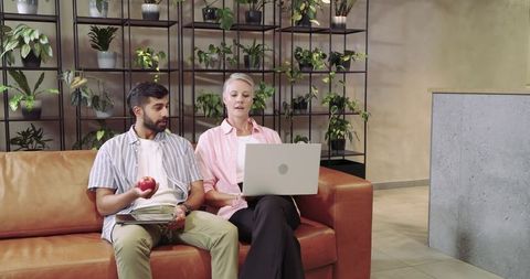 Diverse coworkers collaborating in modern office lounge with technology