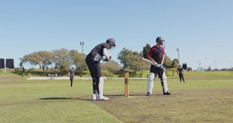Cricketers engaged in intense match on sunny sports field