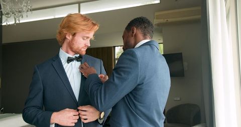 Groom and best man enjoy pre-wedding preparations in elegant suits