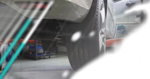 Rear-right wheel and suspension close-up on car lift showing coil spring mounting and alloy wheel
