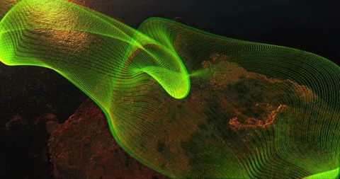 Twisting neon green wireframe ribbon flowing over dark rocky terrain scattering gold particles