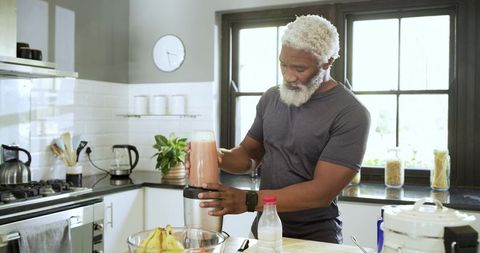 Senior Man Preparing Homemade Smoothie in Modern Kitchen