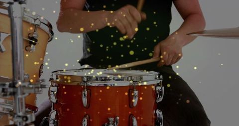 Male drummer playing energetic snare and toms with golden bokeh motion
