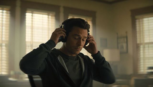 Adjusting Headphones in Sunlit Home Office, Contemplative Adult Male Working at Desk, Calm