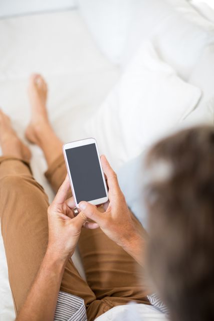 Close-up of man using mobile phone in living room at home