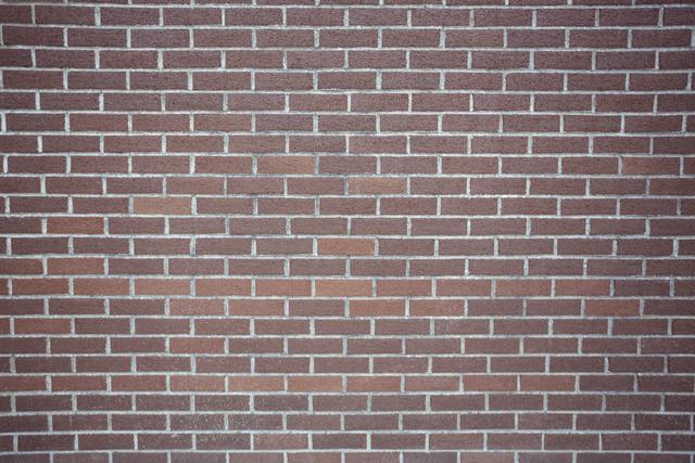 This image shows a full frame view of a new brick wall, highlighting the uniform pattern and texture of the red bricks. Ideal for use in construction, architecture, and urban design projects. It can be used as a background for websites, presentations, or promotional materials related to building materials and masonry.